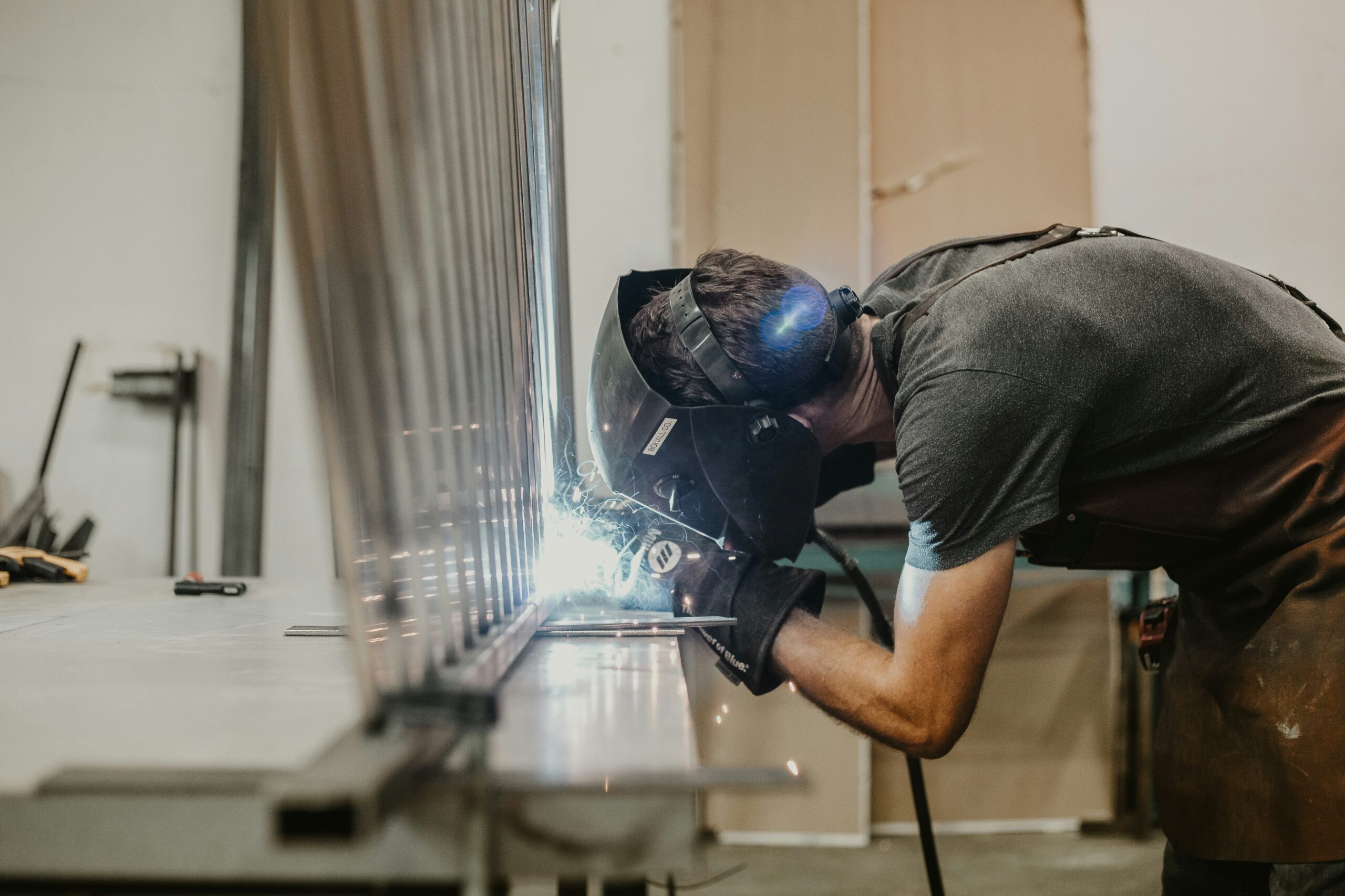 A man welding a large metal piece in a workshop