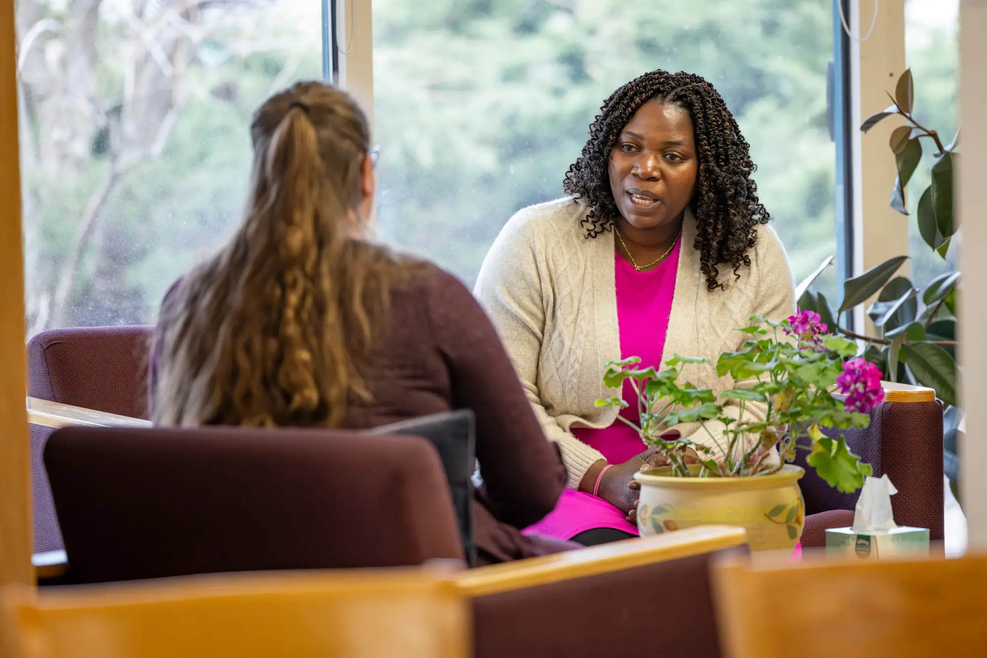 Two people sitting in chairs by a window having a thoughtful conversation.
