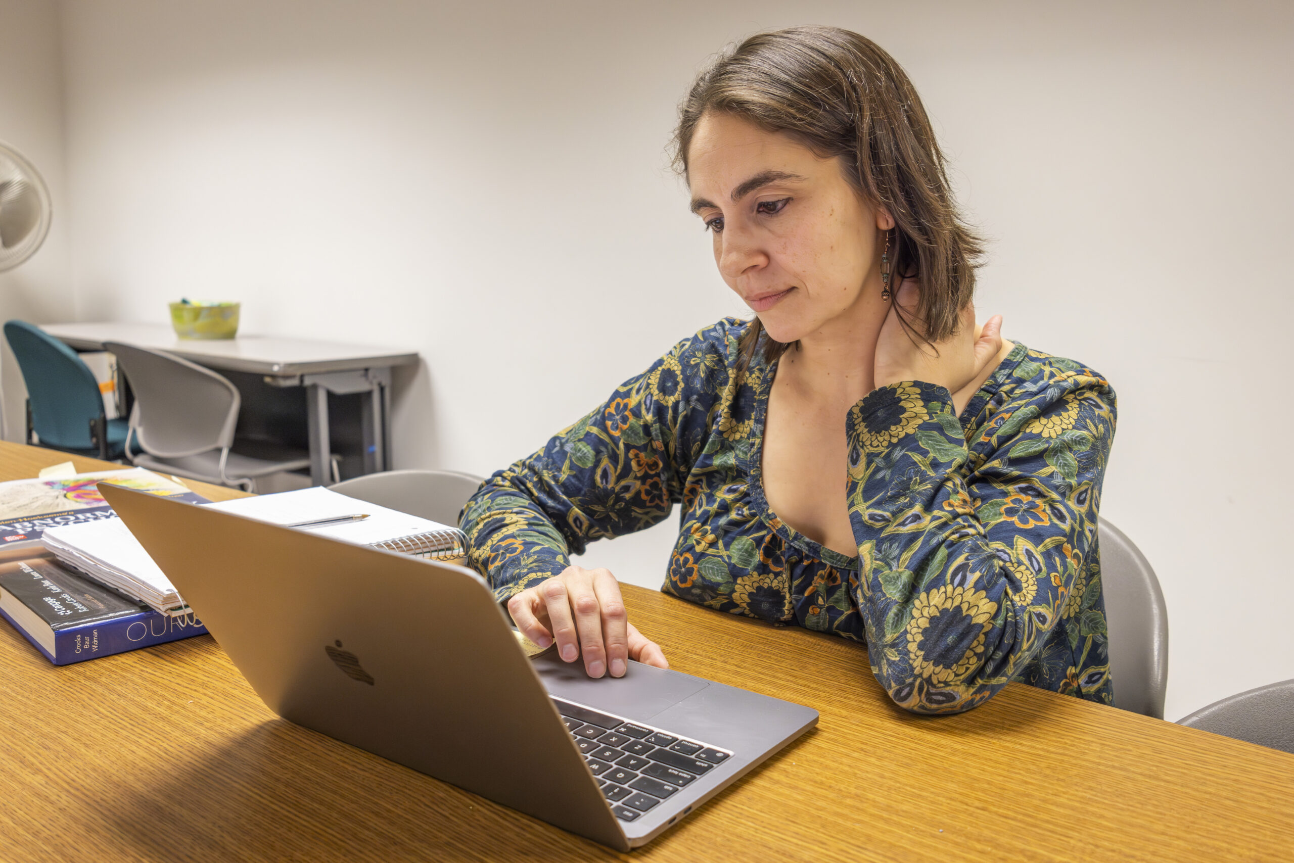 A woman working at a laptop in a well-lit room.