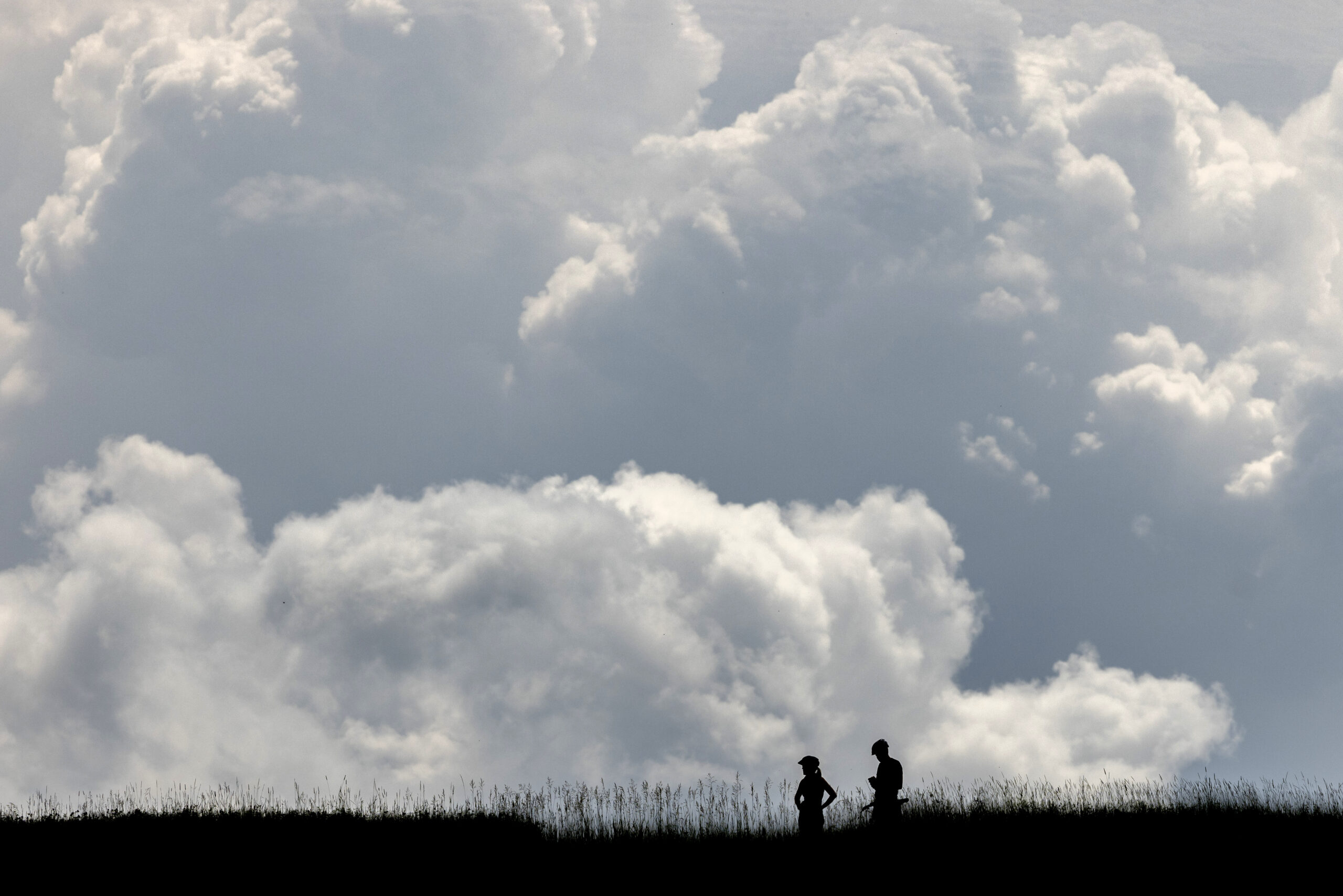 The silhouette of two mountain bikers against a cloudy background