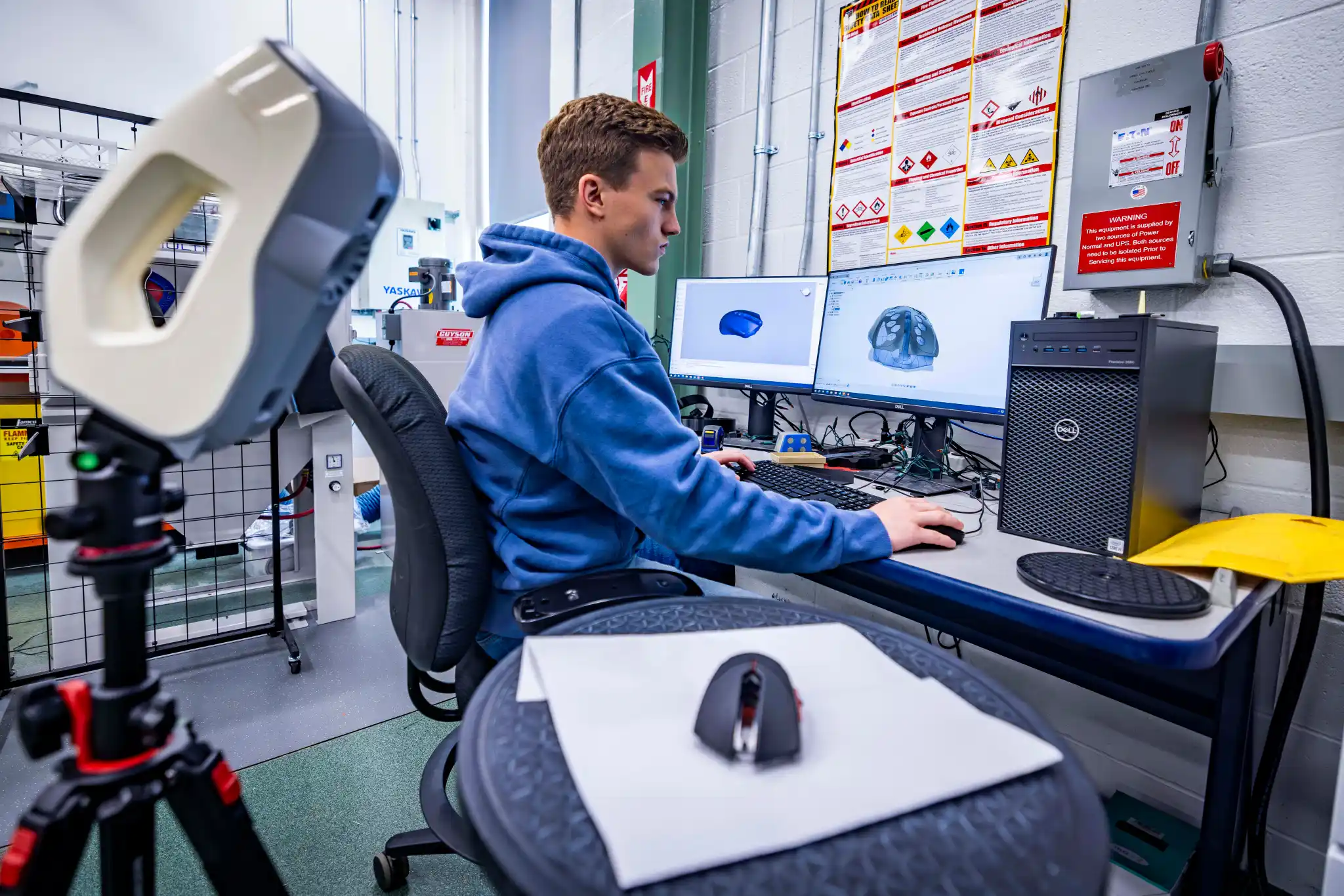 A young man sitting at a computer in a technical lab