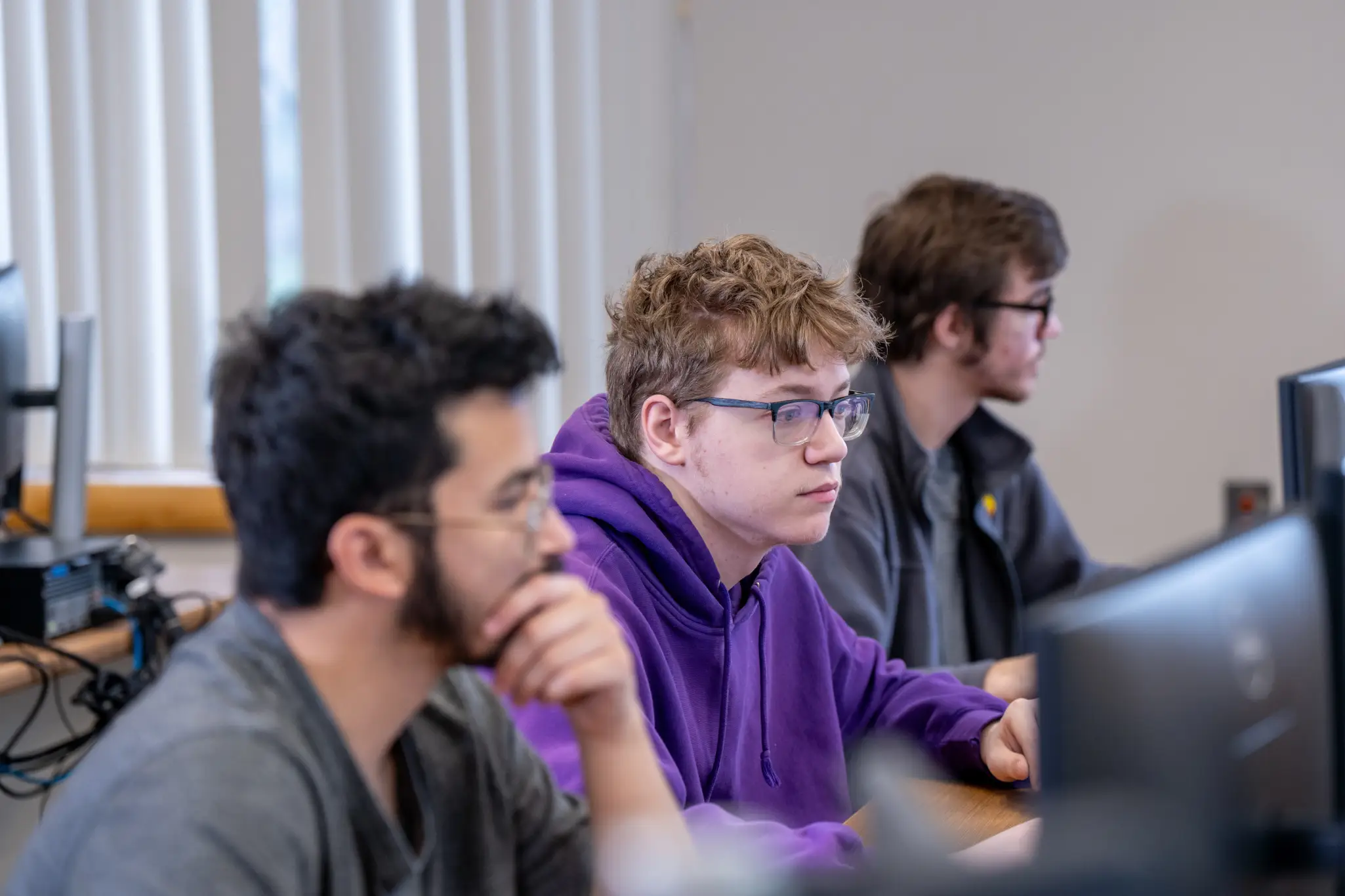 Three young men sitting in a computer lab