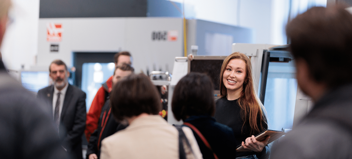 A person holding some notes smiling to the crowd listening to her