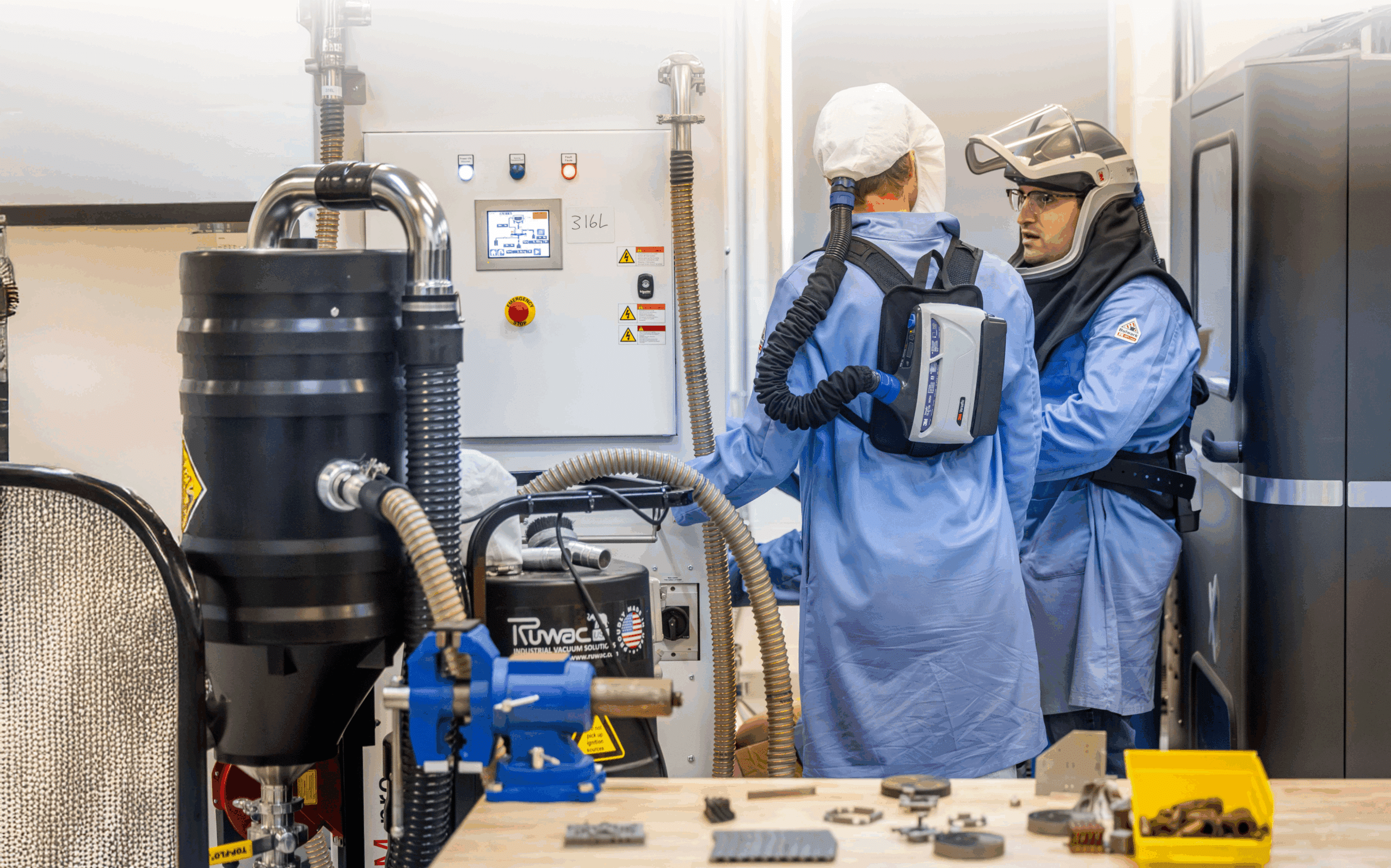 Two people dressed in technical suits with breathing machines, speaking to each other in a laboratory