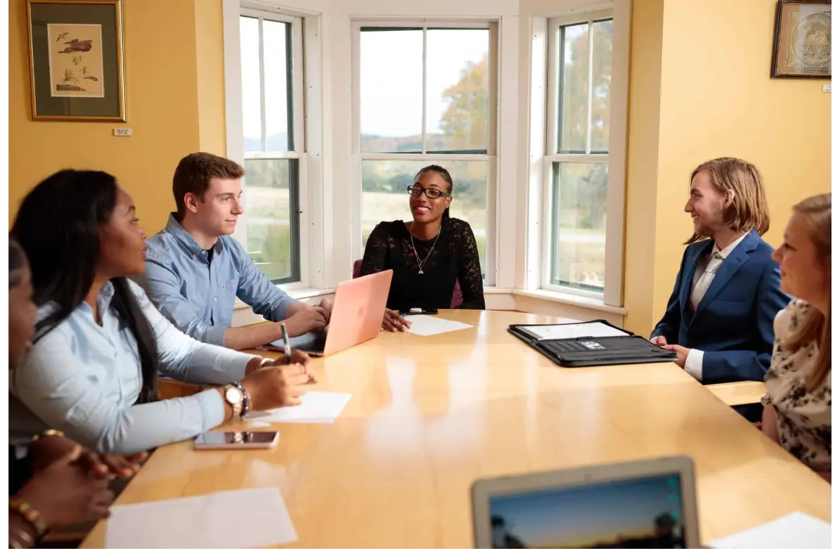 A group of people sitting at a large boardroom table having a discussion