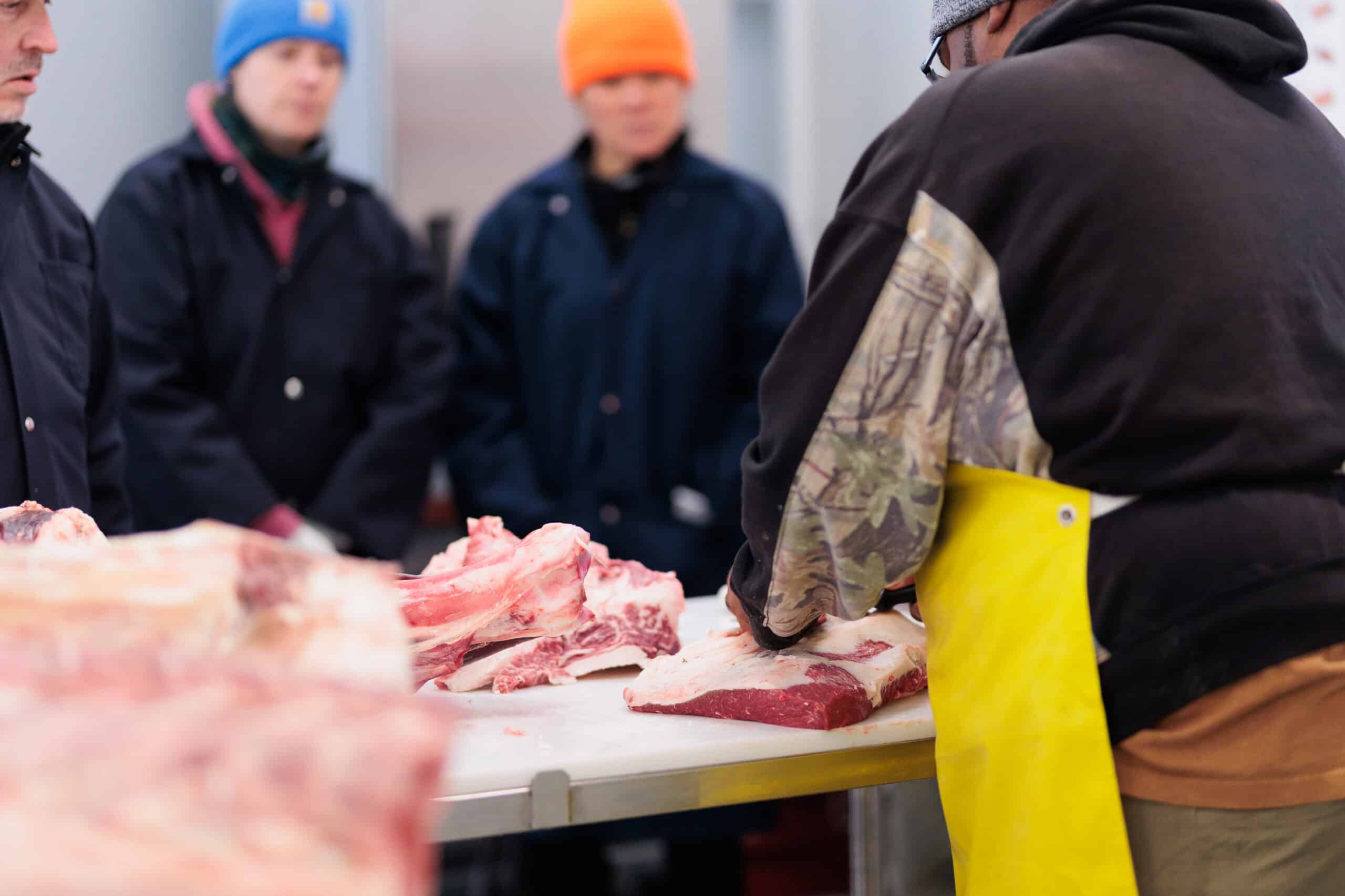 A group of people watching a butchering demonstration