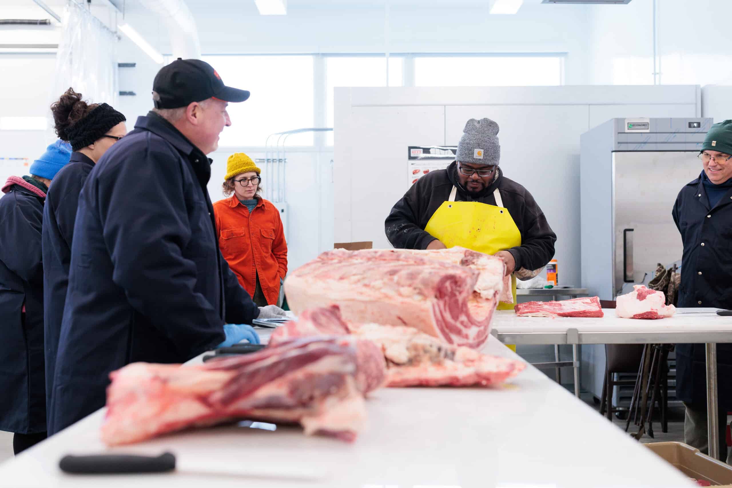 A group of people watching a butchering demonstration