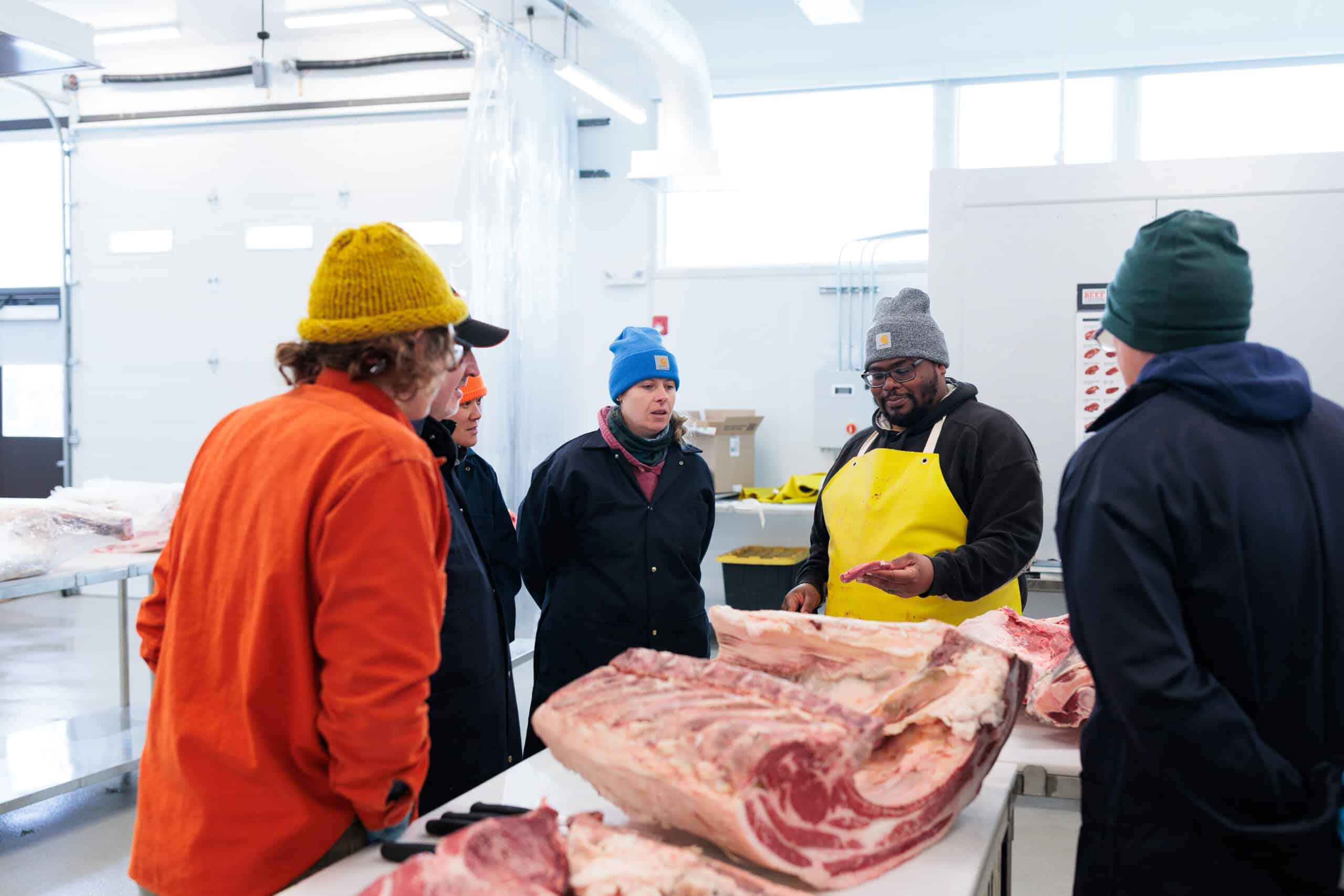 A group of people watching a butchering demonstration