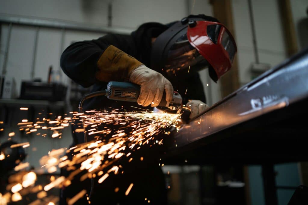 A man using a grinding tool on a large metal component