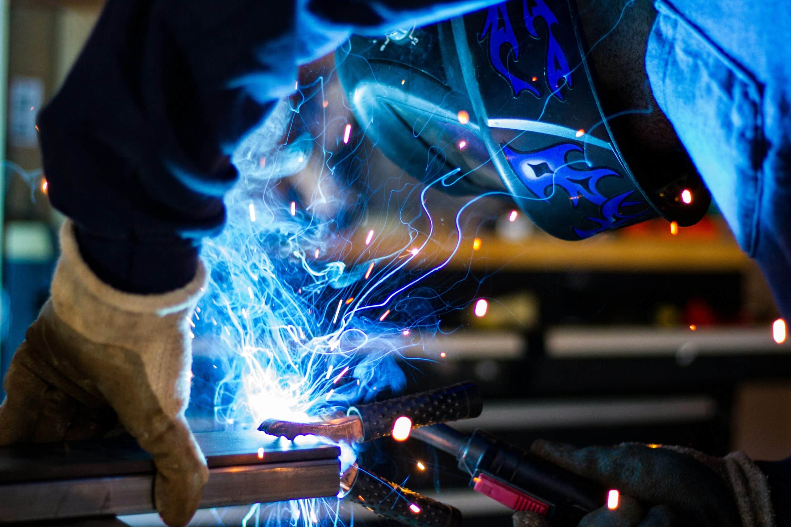 A close up of a person bent over a metal pipe and welding it