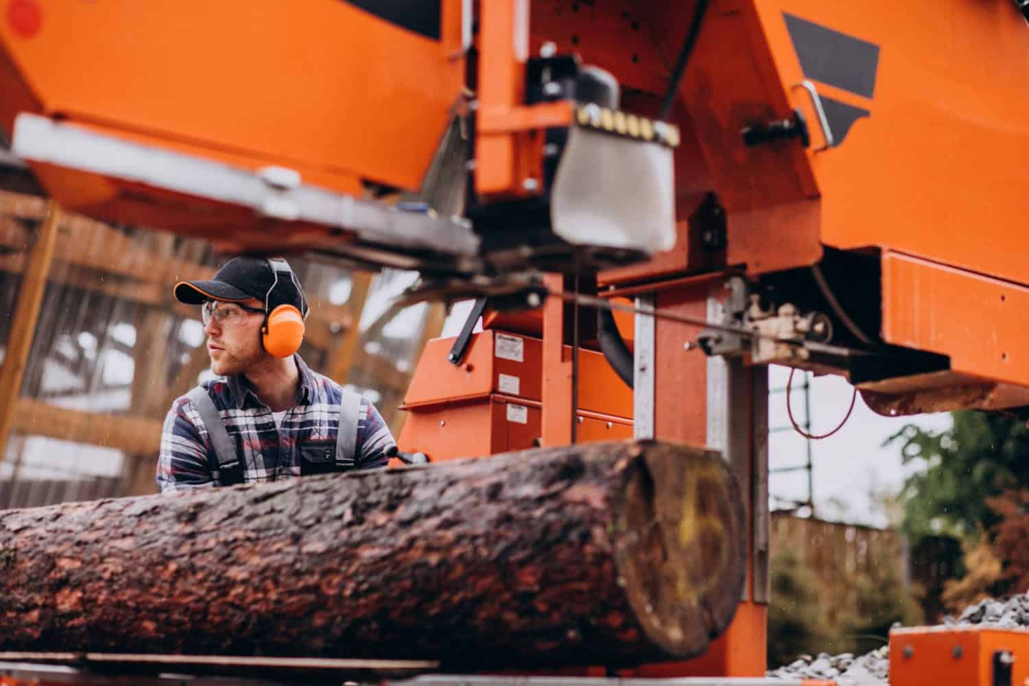 A man pushing a log through a machine at a Sawmill