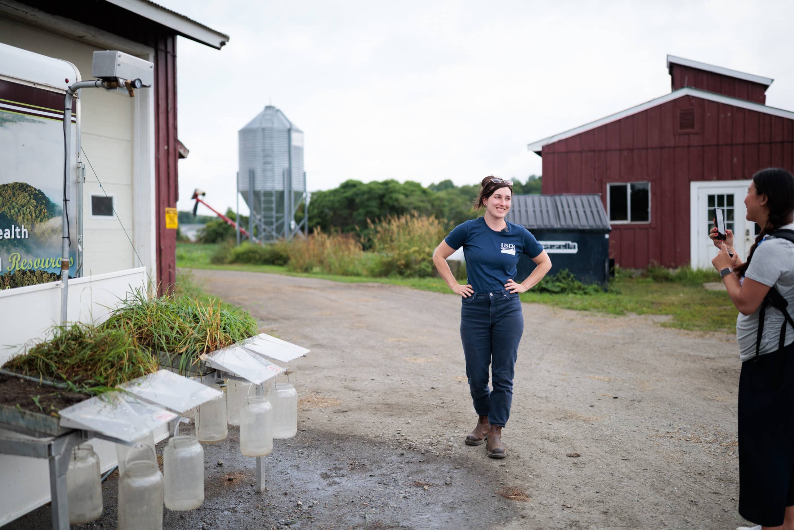 A woman wearing a USDA shirt standing and smiling by a grazing station at the VTSU Randolph campus